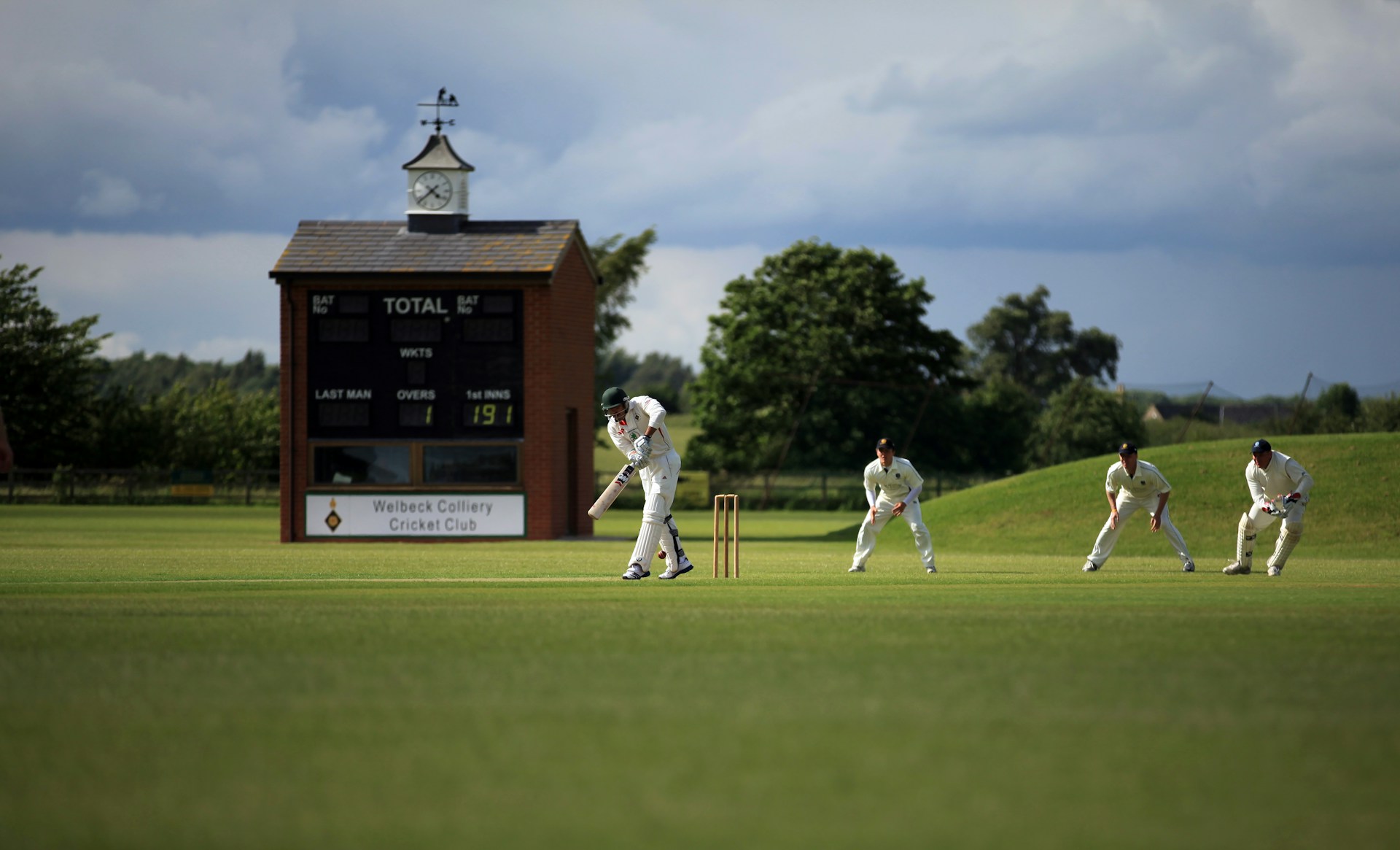 A batter striking the ball in cricket surrounded by fielders